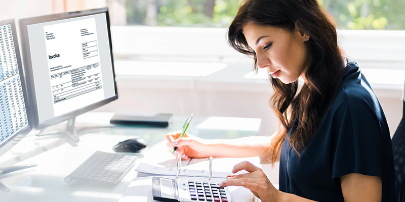 Business Woman at desk with computer, using calculator