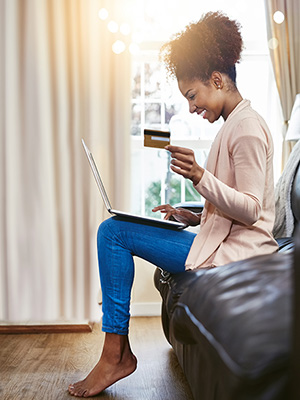 Young woman using laptop and holding credit card